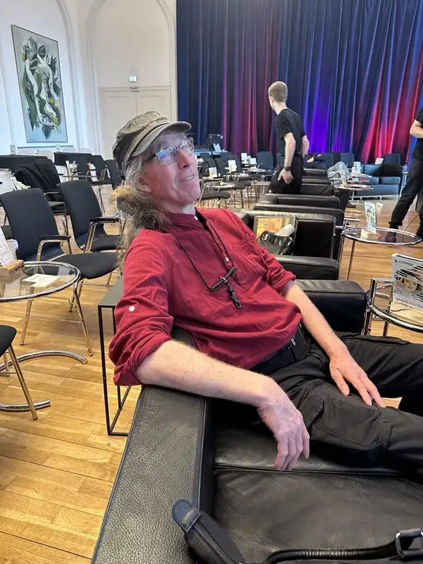 Dett Heidkamp entspannt im Ledersessel im Konzertsaal, im Hintergrund die Bühne